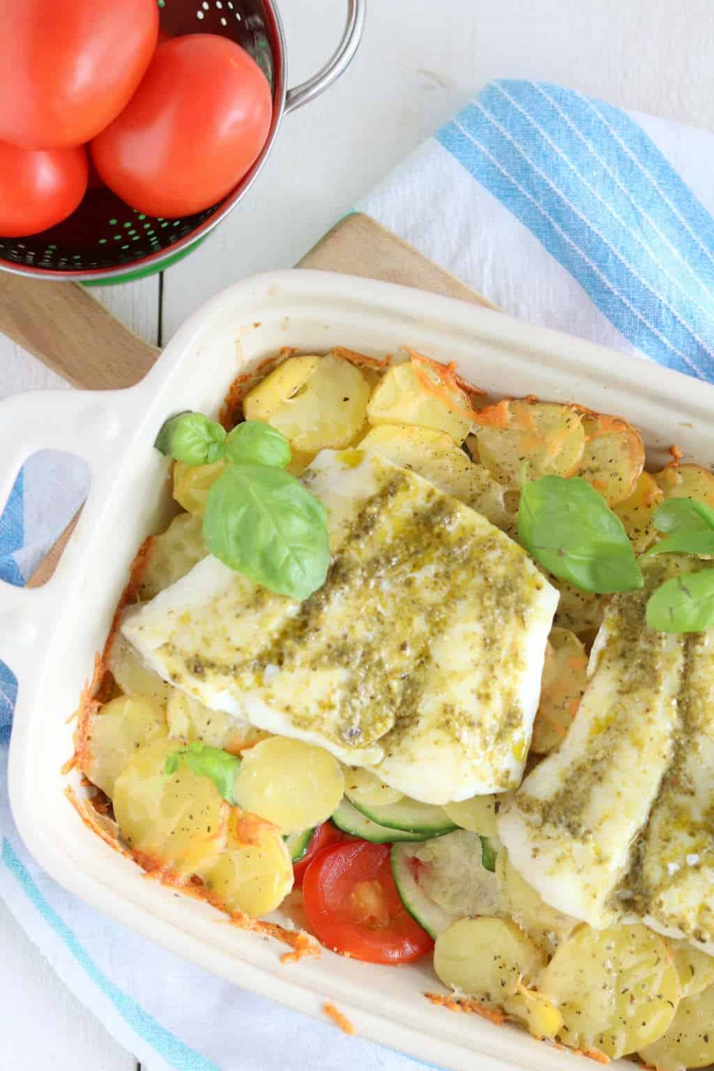 Ovenschotel met kabeljauw, courgette, tomaat en aardppelschijfjes. De vis wordt ingesmeerd met pesto. 
