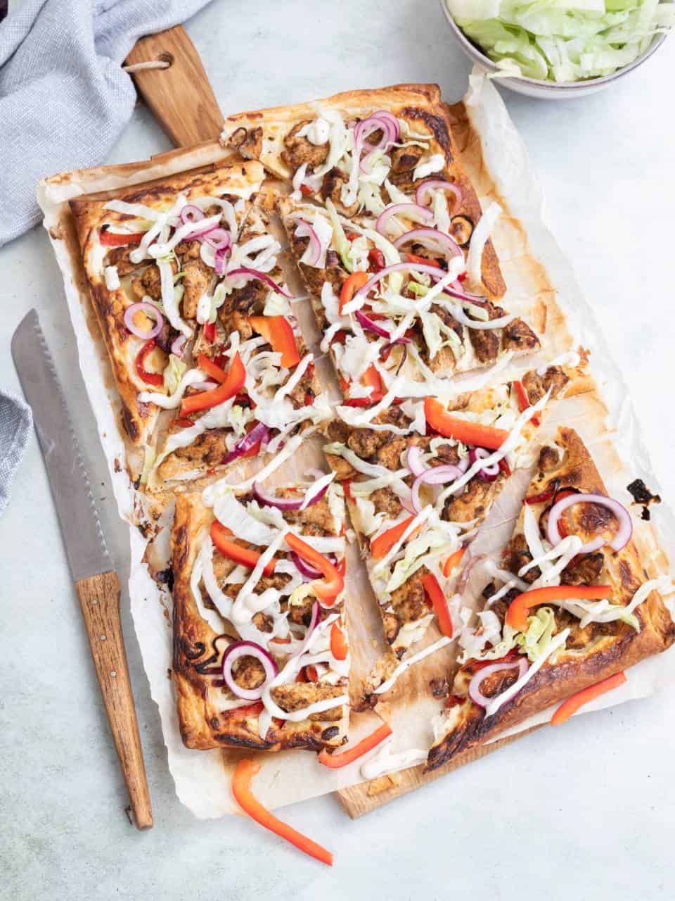 Kip shoarma op een plaattaart met paprika, ui en knoflooksaus