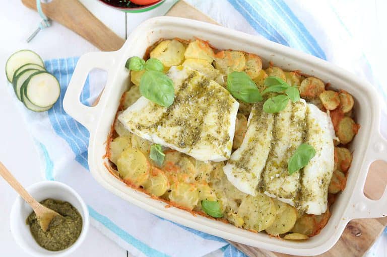 Ovenschotel met kabeljauw, courgette, tomaat en aardppelschijfjes. De vis wordt ingesmeerd met pesto.
